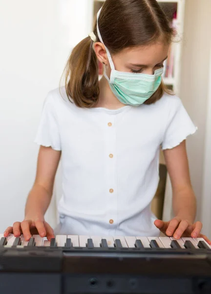 Little girl learning the piano during quarantine. Coronavirus concept.