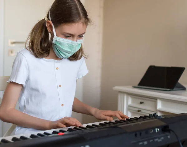 Little girl learning the piano during quarantine. Coronavirus concept.