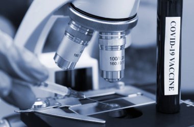 Coronavirüs aşısını mikroskop altında test eden eldiven uzmanı..
