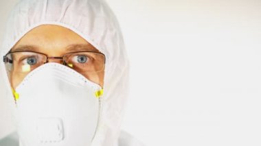Koruyucu takım elbiseli, gözlüklü ve tıbbi maskeli bir erkek doktor..