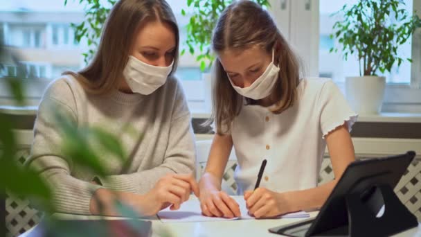 Colegiala con su madre en el aprendizaje a distancia, haciendo la tarea . — Vídeo de stock