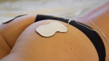 Kalçasında elektrotlar olan bir kadın vücudu. Elektriksel kas uyarılması.