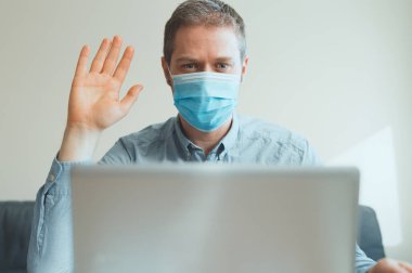 Tıbbi maskeli adam içeriyi arayan bir video aracılığıyla selamlıyor..