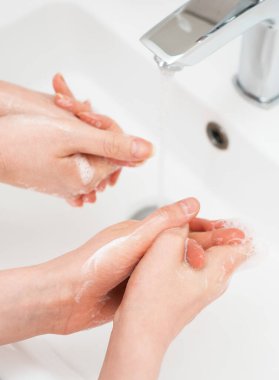 Aile evde musluğun altında ellerini yıkıyor. Coronavirus koruma kavramı.