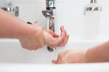 Aile evde musluğun altında ellerini yıkıyor. Coronavirus koruma kavramı.