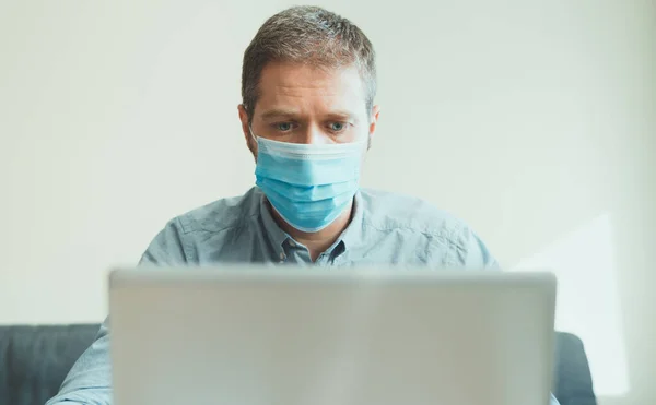 Man in medical mask working on the computer indoors.