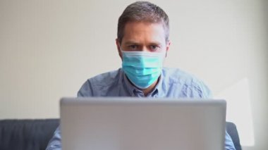 İçerideki bilgisayarda çalışan tıbbi maskeli adam..