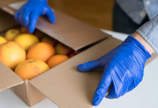 保護医療用手袋のボランティア果物を寄付箱に入れる — ストック写真