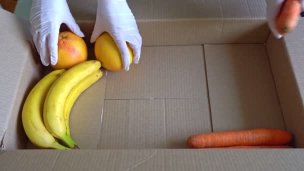 戴着防护医疗手套的志愿者把水果和蔬菜放在捐赠箱中 — 图库视频影像