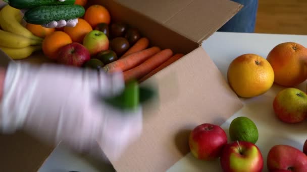 戴着防护医疗手套的志愿者从捐赠箱中取出水果和蔬菜 — 图库视频影像