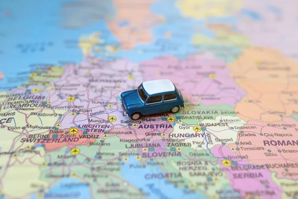 Small toy retro car on Europe map in Austria. Travel by car concept.