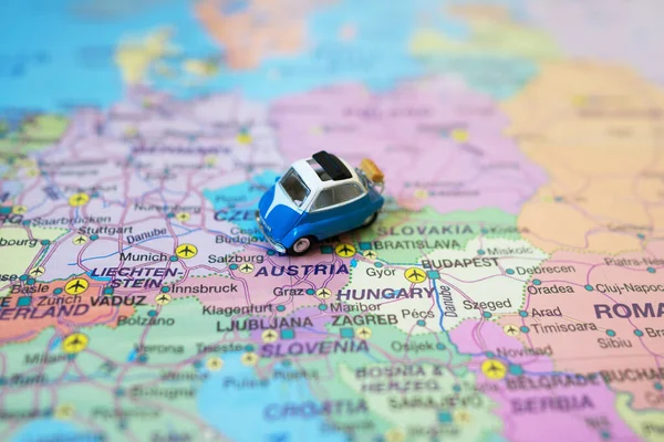 Small toy retro car on Europe map in Austria. Travel by car concept.