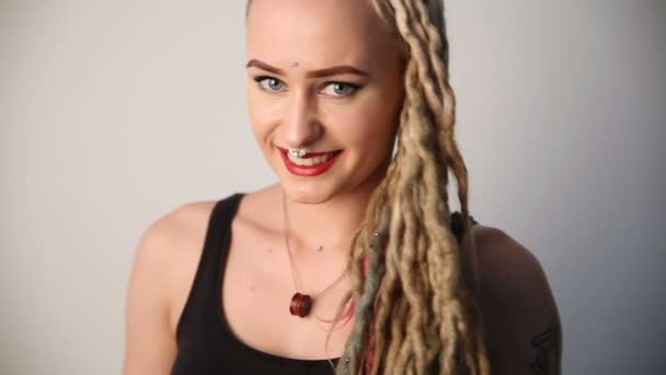 Modern youth. portrait of a cheerful beautiful girl of unusual appearance - dreads, piercings and tattoos. — Stock Video