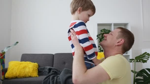 Zorg en liefde voor kinderen in het gezin. Papa is het hebben van plezier met zijn zoontje in de huiskamer. — Stockvideo