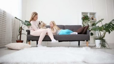 Evcil aile hayatı. Anne ve kızı okşadı ve oturma odasında kanepede bir golden retriever sarılmak.