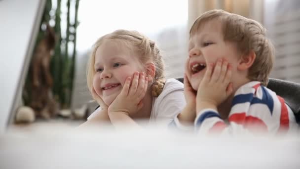 Computer nella vita dei bambini moderni. fratellino e sorella che guardano cartoni animati sul computer portatile, sdraiato sul letto in camera da letto . — Video Stock