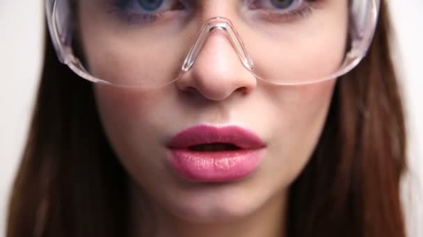 Gesicht einer sexy Frau in Baubrille in Großaufnahme. das Mädchen kaut erotisch Kaugummi. — Stockvideo