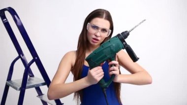 seksi kız bir merdiven ile beyaz bir stüdyo bir matkap ile poz. kavram - güzellik ve güç, feminizm