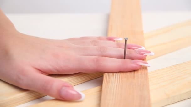 一个性感的女人在木制建筑中用锤子锤钉子。手与美丽的指甲特写. — 图库视频影像