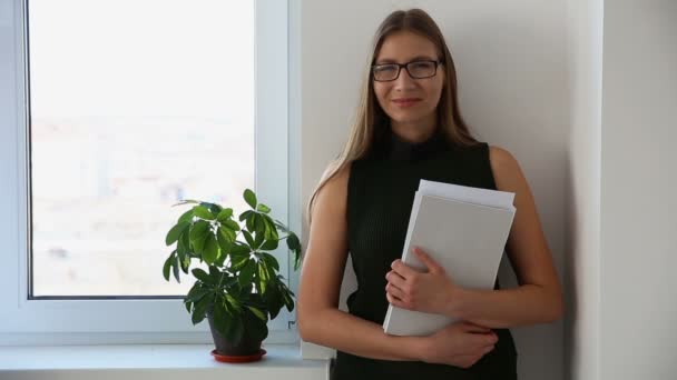 Portrait de fille d'affaires avec des documents près de la fenêtre dans le bureau. heureux employé de bureau femme . — Video