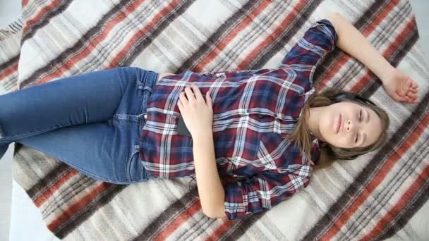 Електронні пристрої в житті сучасної молоді. молода дівчина-підліток відпочиває вдома на ліжку з мобільним телефоном . — стокове відео