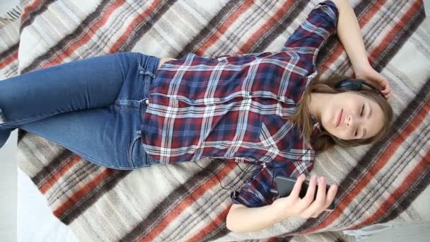 Ηλεκτρονικές συσκευές στη ζωή της σύγχρονης νεολαίας. νέα κοπέλα έφηβων, ξεκουράζονται στο σπίτι στο κρεβάτι με το κινητό τηλέφωνο. — Αρχείο Βίντεο