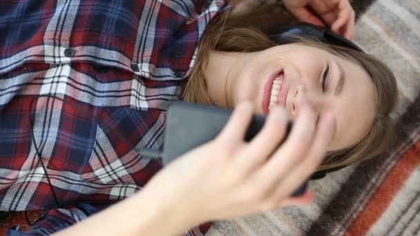 Elektronická zařízení v životě moderní mládeže. mladá dospívající dívka odpočívá doma v posteli s mobilním telefonem. — Stock video