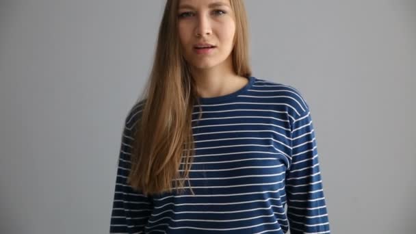 Portrait d'une fille blonde d'apparence européenne en vêtements décontractés sur fond gris — Video