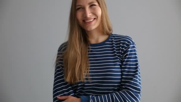 Retrato de una chica rubia de aspecto europeo en ropa casual sobre un fondo gris — Vídeo de stock