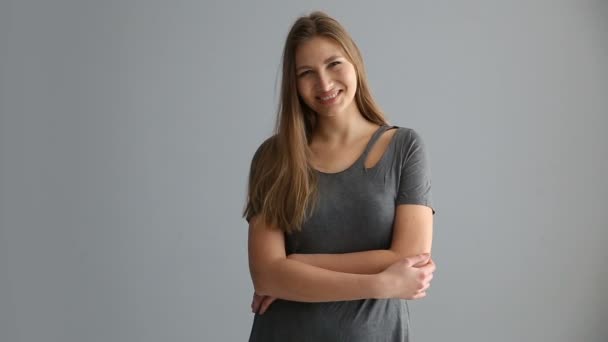 Retrato de una chica rubia de aspecto europeo en ropa casual sobre un fondo gris — Vídeos de Stock