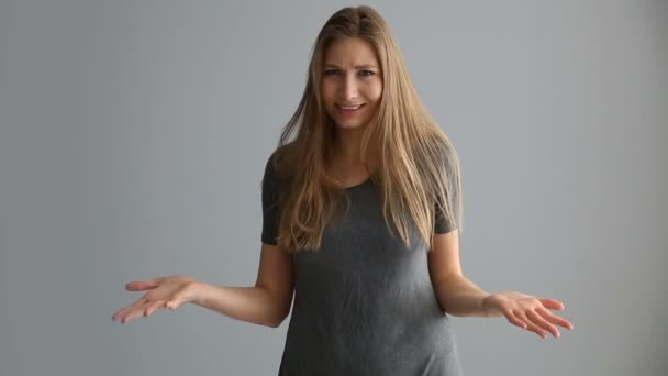 Portret van een blond meisje van Europees uiterlijk in casual kleding op een grijze achtergrond — Stockvideo