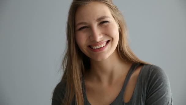 Portret van een blond meisje van Europees uiterlijk in casual kleding op een grijze achtergrond — Stockvideo