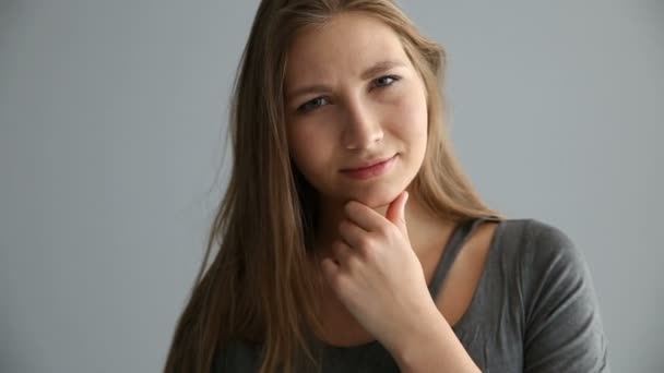 Retrato de uma menina loira de aparência europeia em roupas casuais em um fundo cinza — Vídeo de Stock