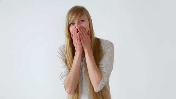 Belle fille aux cheveux longs d'apparence européenne avec des cheveux blonds posant contre un mur blanc. émotions des acteurs - choc, surprise, plaisir joyeux — Video