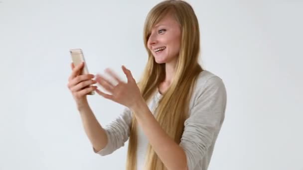 现代青年。美丽的长头发的欧洲外观的女孩与金发意味深长谈论视频通信智能手机在白色墙壁附近 — 图库视频影像