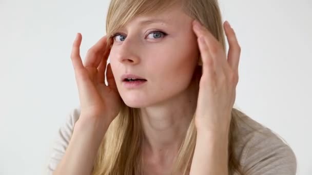 Beautiful long-haired girl of European appearance with blond hair looks at her face closeup — Stock Video