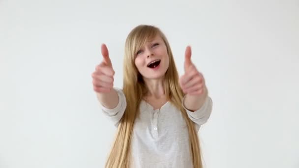 Krásné dlouhé vlasy dívka Evropského vzhledu s plavými vlasy, objevovat palce nad bílé abackground — Stock video
