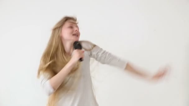 Alegre atractivo adolescente chica cantar canción celebración peine como un micrófono sobre blanco fondo . — Vídeos de Stock