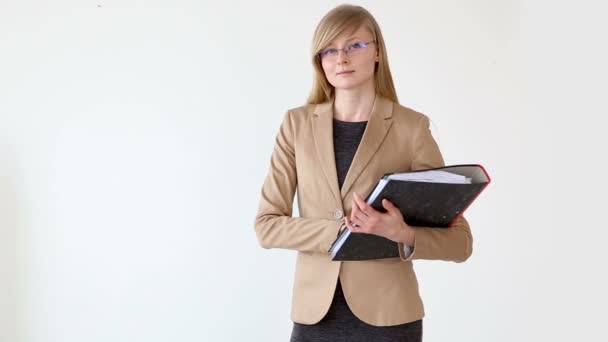 Giovane bella donna in stile business con occhiali e documenti in mano posa vicino sfondo bianco — Video Stock