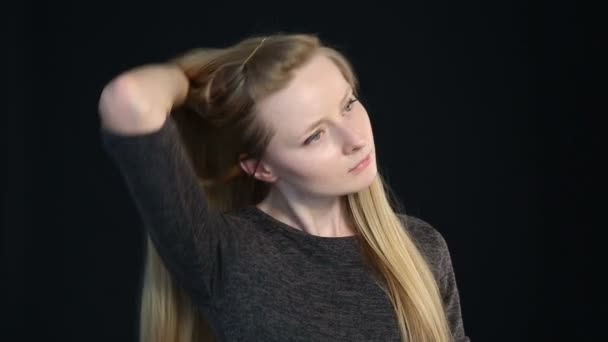 Emotionele portret van een blond meisje op een zwarte achtergrond — Stockvideo