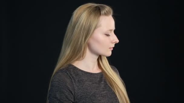 Emotionele portret van een blond meisje op een zwarte achtergrond — Stockvideo