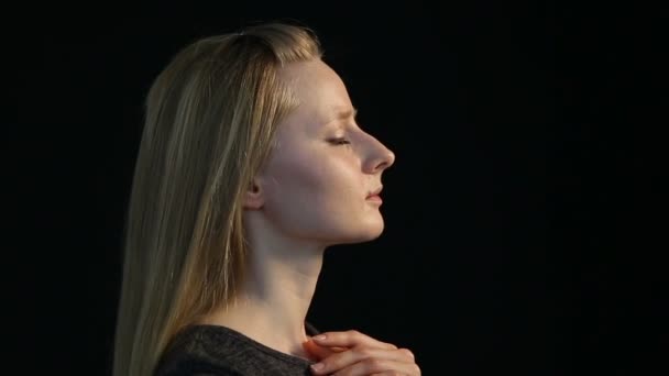 Emotionele portret van een blond meisje op een zwarte achtergrond — Stockvideo