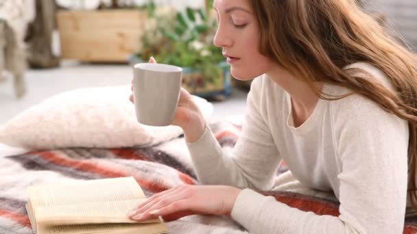 Mujer bebe café y lee libro en la cama dormitorio — Vídeos de Stock