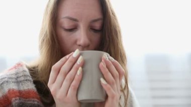 basit bir kadın sıcak yün battaniyeye sarılmış çay içer