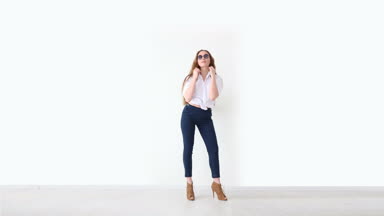 moda modern gençlik. şık kız kot pantolon, beyaz gömlek, deri sırt çantası ve gözlük ile beyaz duvara poz.