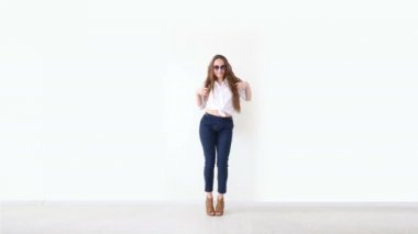 moda modern gençlik. şık kız kot pantolon, beyaz gömlek, deri sırt çantası ve gözlük ile beyaz duvara poz.