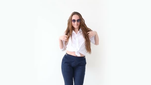 Módní moderní mládeže. elegantní dívka pózuje proti bílé zdi v džíny, bílé tričko s kožený batoh a brýle.