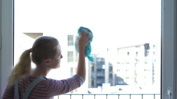 Молодая женщина чистит окно — стоковое видео