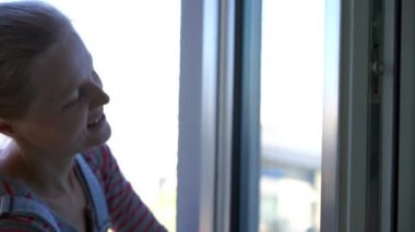 Pencereyi temizleyen genç kadın, ağır çekimde.