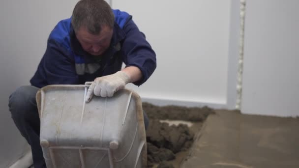 Reparatie van appartementen en huizen. de bouwer giet en egaliseert de betonnen vloer. — Stockvideo